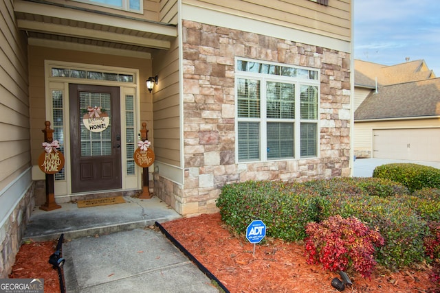 entrance to property featuring a garage and stone siding