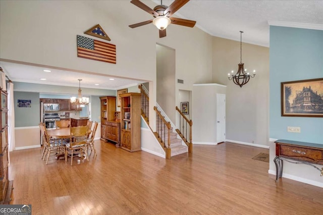 dining space with baseboards, stairs, ornamental molding, ceiling fan with notable chandelier, and light wood-style floors