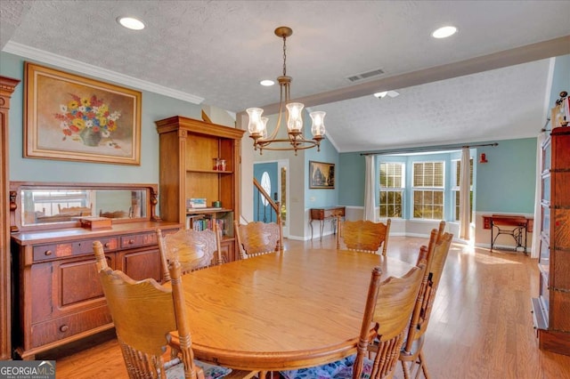 dining room with light wood finished floors, visible vents, crown molding, an inviting chandelier, and a textured ceiling