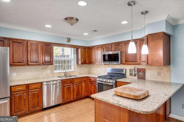 kitchen featuring light wood-type flooring, a sink, stainless steel appliances, a peninsula, and hanging light fixtures