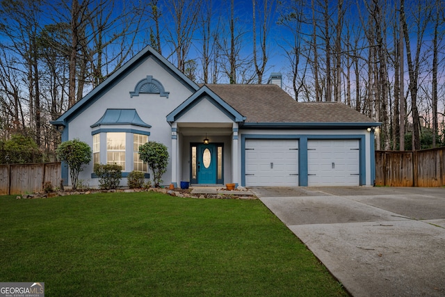 view of front of home featuring an attached garage, driveway, a front lawn, and fence