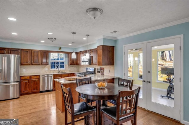 kitchen with light wood finished floors, stainless steel appliances, decorative backsplash, french doors, and crown molding