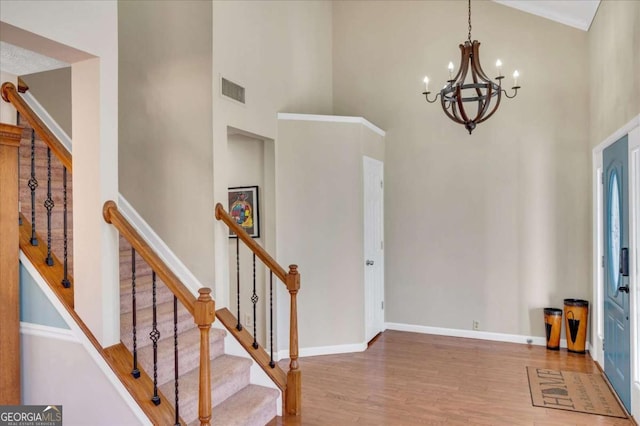 foyer with wood finished floors, visible vents, baseboards, a high ceiling, and a chandelier