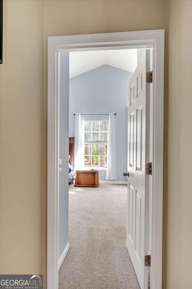 corridor featuring baseboards, carpet floors, and lofted ceiling