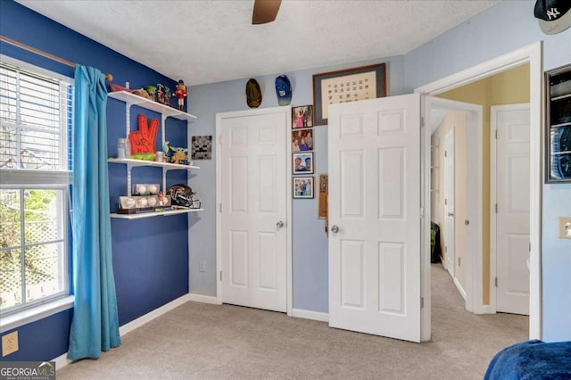unfurnished bedroom featuring carpet flooring, a ceiling fan, baseboards, and a textured ceiling