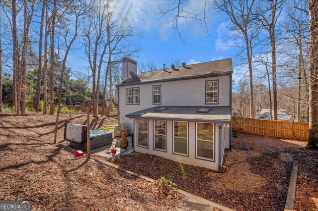 back of property with a chimney and fence