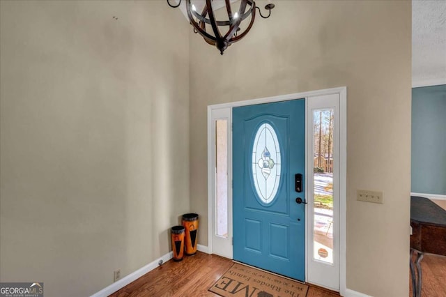 entrance foyer featuring a notable chandelier, baseboards, and wood finished floors