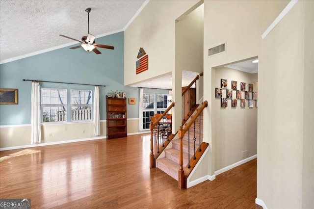 interior space with crown molding, plenty of natural light, wood finished floors, and visible vents