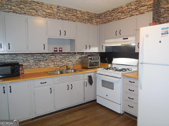 kitchen featuring white appliances, white cabinetry, sink, and dark hardwood / wood-style flooring