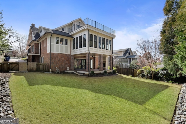 back of property with a yard and a sunroom