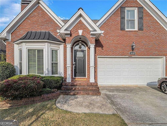 traditional home with brick siding, a chimney, concrete driveway, a standing seam roof, and a garage