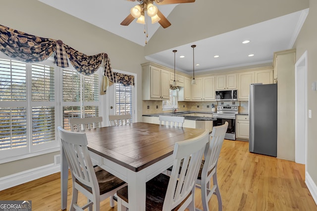 dining area featuring vaulted ceiling, ornamental molding, light wood-style flooring, and a ceiling fan