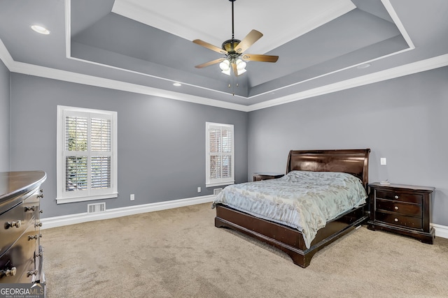 carpeted bedroom with visible vents, a tray ceiling, and baseboards