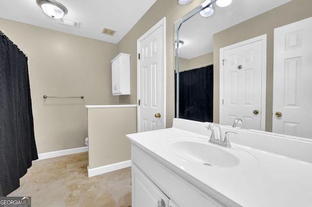 bathroom featuring toilet, vanity, visible vents, and baseboards