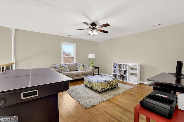 living area with ceiling fan, wood finished floors, visible vents, and baseboards