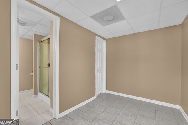 unfurnished room featuring a drop ceiling, baseboards, and light tile patterned floors