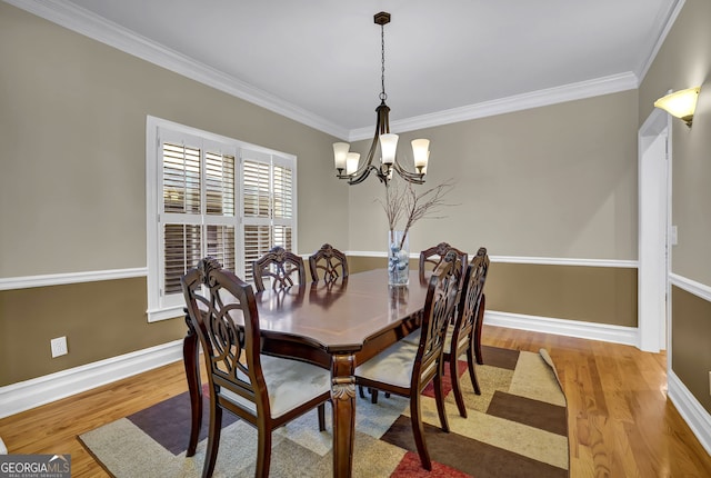 dining area with ornamental molding, baseboards, an inviting chandelier, and wood finished floors