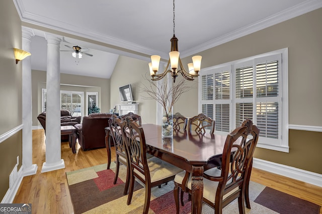 dining space with ornate columns, vaulted ceiling, light wood finished floors, and ceiling fan with notable chandelier