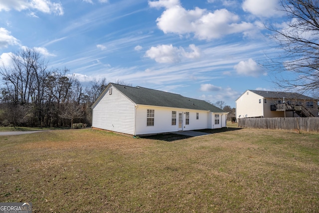 rear view of property featuring fence and a yard