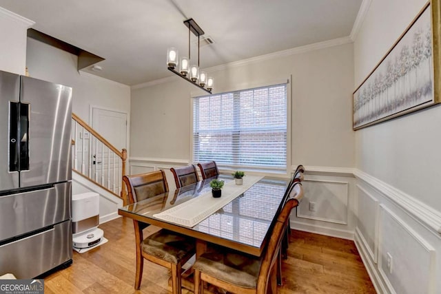 dining room featuring light hardwood / wood-style floors, an inviting chandelier, and ornamental molding