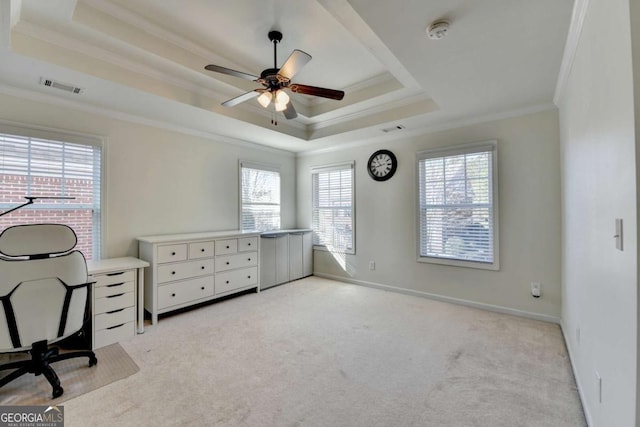 unfurnished office featuring ornamental molding, light colored carpet, ceiling fan, and a raised ceiling