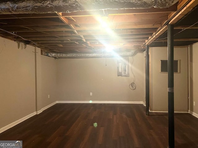 basement featuring electric panel and dark hardwood / wood-style flooring