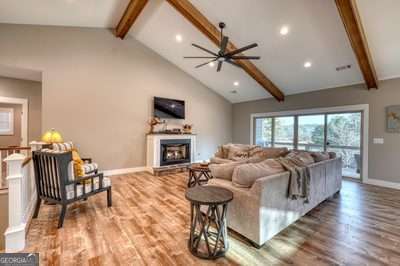 living room with high vaulted ceiling, hardwood / wood-style flooring, ceiling fan, and beam ceiling