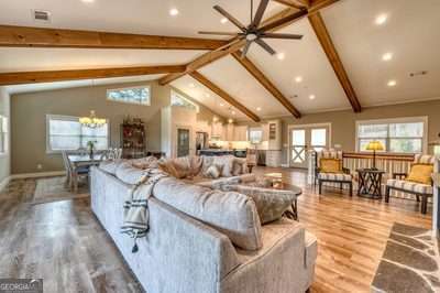 living room featuring hardwood / wood-style floors, plenty of natural light, lofted ceiling with beams, and a notable chandelier