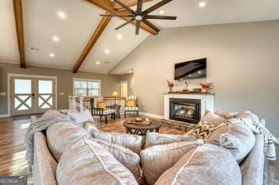 living room featuring french doors, hardwood / wood-style floors, and vaulted ceiling with beams