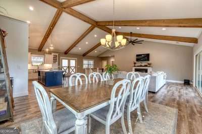 dining space with light hardwood / wood-style floors, a chandelier, and lofted ceiling with beams