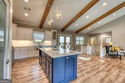 kitchen featuring white cabinetry, vaulted ceiling with beams, a kitchen island, and light hardwood / wood-style flooring