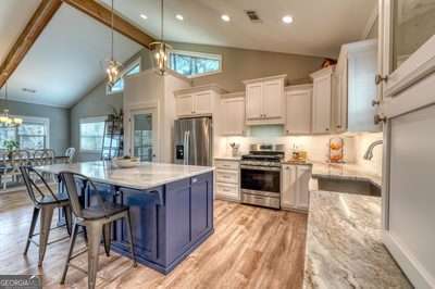 kitchen with white cabinetry, stainless steel appliances, pendant lighting, and sink