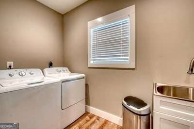 clothes washing area with washer and dryer, sink, and light hardwood / wood-style flooring