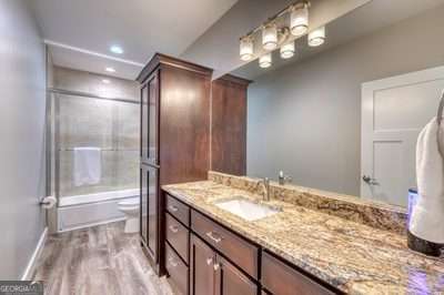 full bathroom featuring toilet, vanity, hardwood / wood-style floors, and enclosed tub / shower combo