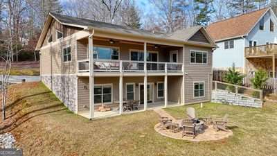 back of property featuring an outdoor fire pit, a lawn, a patio area, and a balcony