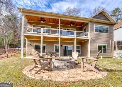 rear view of property with ceiling fan, a patio, an outdoor fire pit, and a balcony