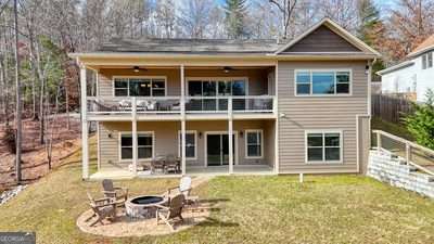 back of house featuring a lawn, a fire pit, a balcony, and a patio area