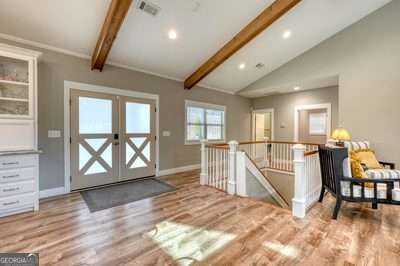 foyer featuring light hardwood / wood-style floors, vaulted ceiling with beams, and french doors