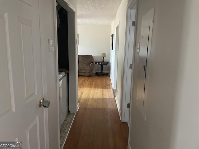 corridor with a textured ceiling and wood finished floors