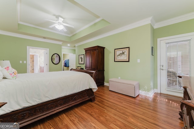 bedroom featuring ornamental molding, light hardwood / wood-style flooring, and a raised ceiling