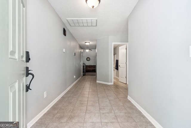 hallway featuring a textured ceiling and light tile patterned flooring