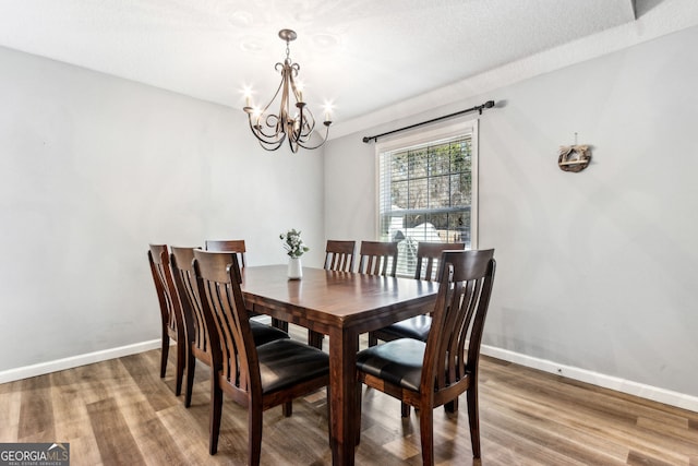 dining space with an inviting chandelier, a textured ceiling, and hardwood / wood-style floors