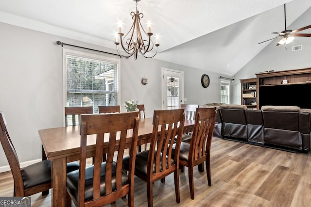 dining room with ceiling fan with notable chandelier, light hardwood / wood-style flooring, and lofted ceiling