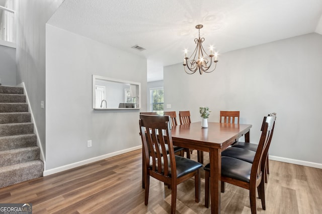 dining room featuring hardwood / wood-style flooring, a chandelier, and a textured ceiling