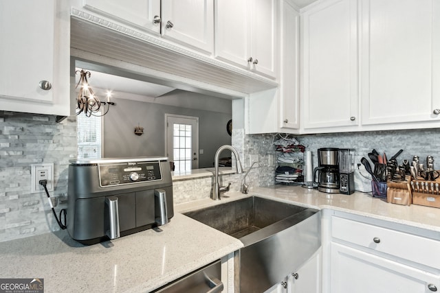 kitchen featuring white cabinets, sink, and light stone counters