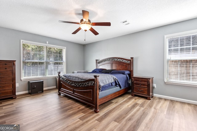 bedroom featuring light hardwood / wood-style flooring, ceiling fan, and a textured ceiling