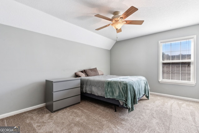 bedroom with ceiling fan, vaulted ceiling, a textured ceiling, and light colored carpet