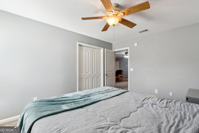 carpeted bedroom with a closet, ceiling fan, and a textured ceiling