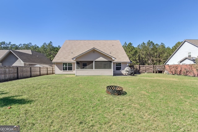 rear view of house with a sunroom, a lawn, and an outdoor fire pit