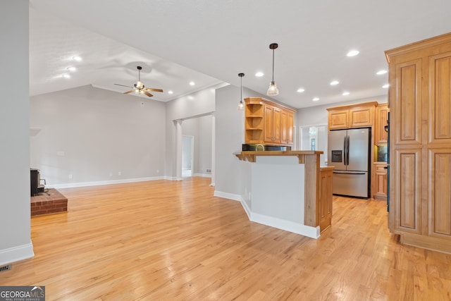 kitchen featuring light hardwood / wood-style flooring, hanging light fixtures, stainless steel refrigerator with ice dispenser, ceiling fan, and a wood stove